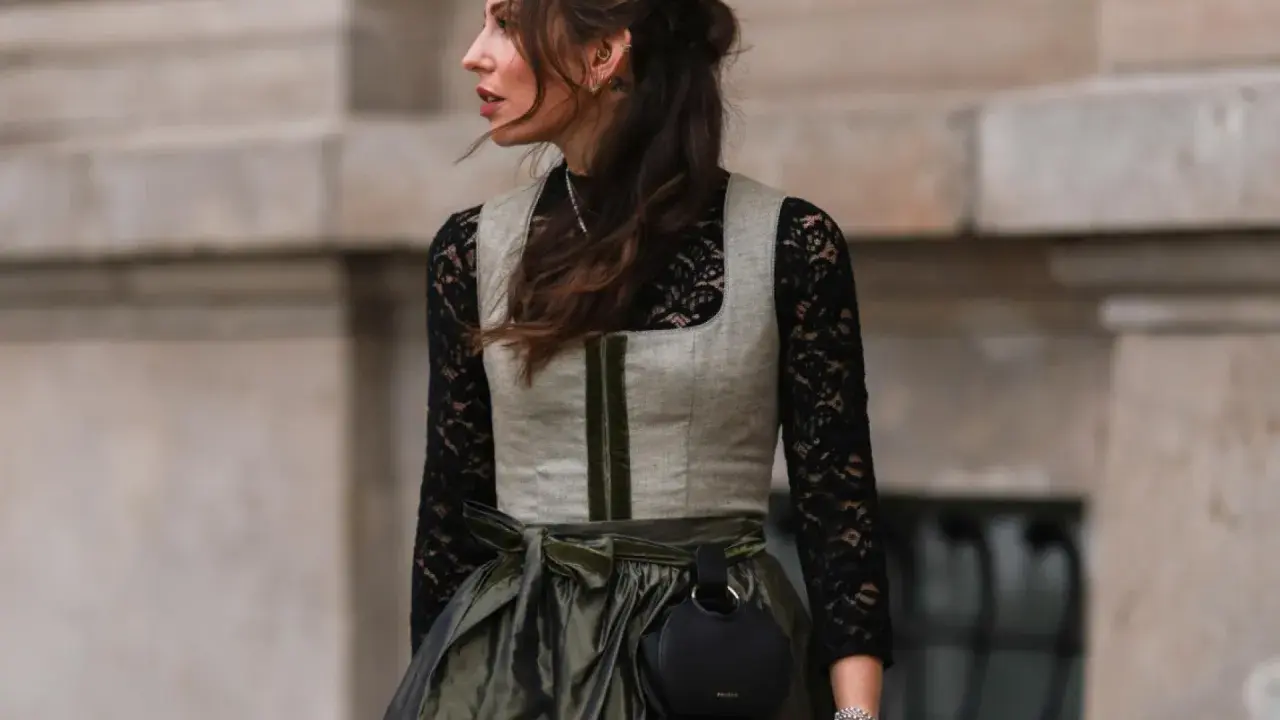 Eine Frau trägt eine graue Weste über einer schwarzen Spitzenbluse. So lässt sich die schwarze Bluse kombinieren für einen modernen Look.
