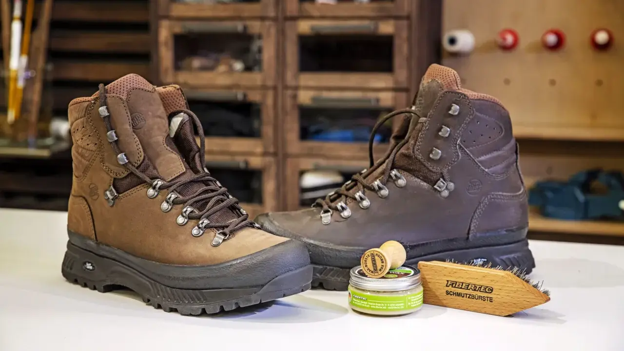 Braune Wanderschuhe, daneben ein Wachs und eine Bürste zur Pflege. So bleiben deine adidas Terrex Stiefel wie neu, auch nach der nächsten "Waschmaschine" aus Schlamm und Matsch.