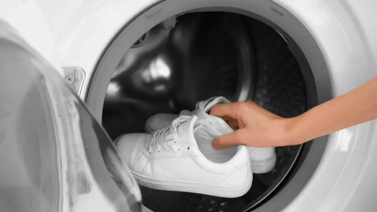 Weiße Sneaker werden in die Waschmaschine gelegt, um sie wieder sauber zu bekommen.