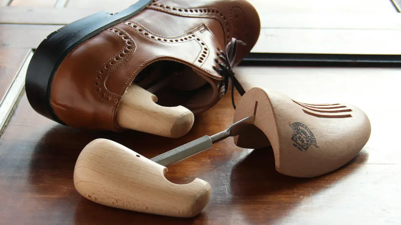 Holz-Schuhspanner für elegante Schuhe, die auch als Schuhspanner für Wanderschuhe dienen könnten, liegen neben einem braunen Lederschuh.