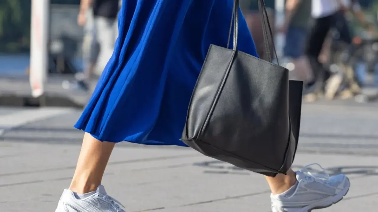Ein blaues Kleid mit weißen Sneakern zum Kleid und einer schwarzen Tasche.