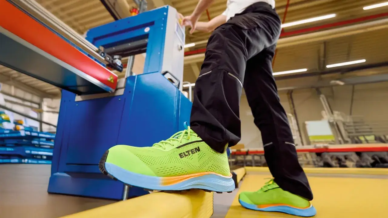 Arbeiter in leuchtend grünen Sicherheitsschuhen von ELTEN an einer Maschine. Seit wann gibt es Schuhe? Schon seit der Steinzeit, um die Füße zu schützen.