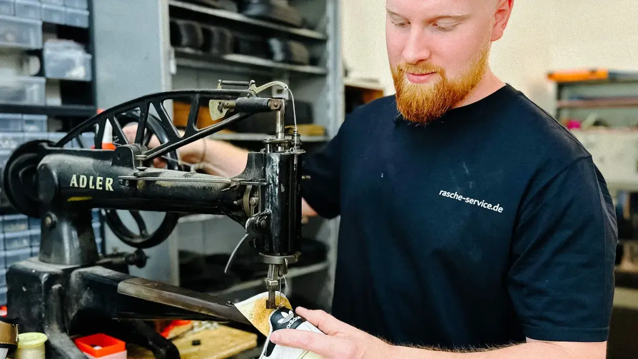 Ein Schuster repariert Schuhe an einer alten Nähmaschine. Er ist ein Handwerker, der sich um das Schuhwerk kümmert.