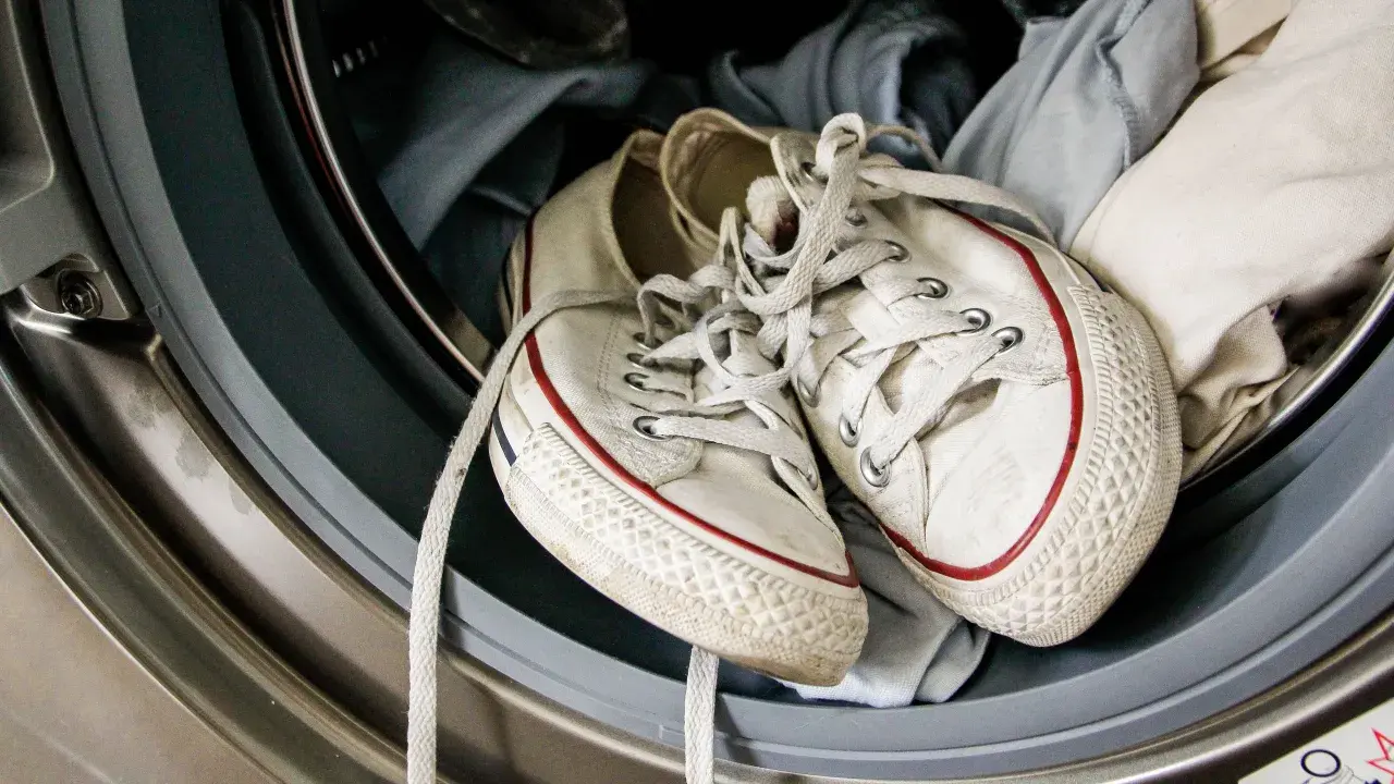 Weiße Superga Schuhe mit roten Streifen warten in der Waschmaschine auf ihren Waschgang.