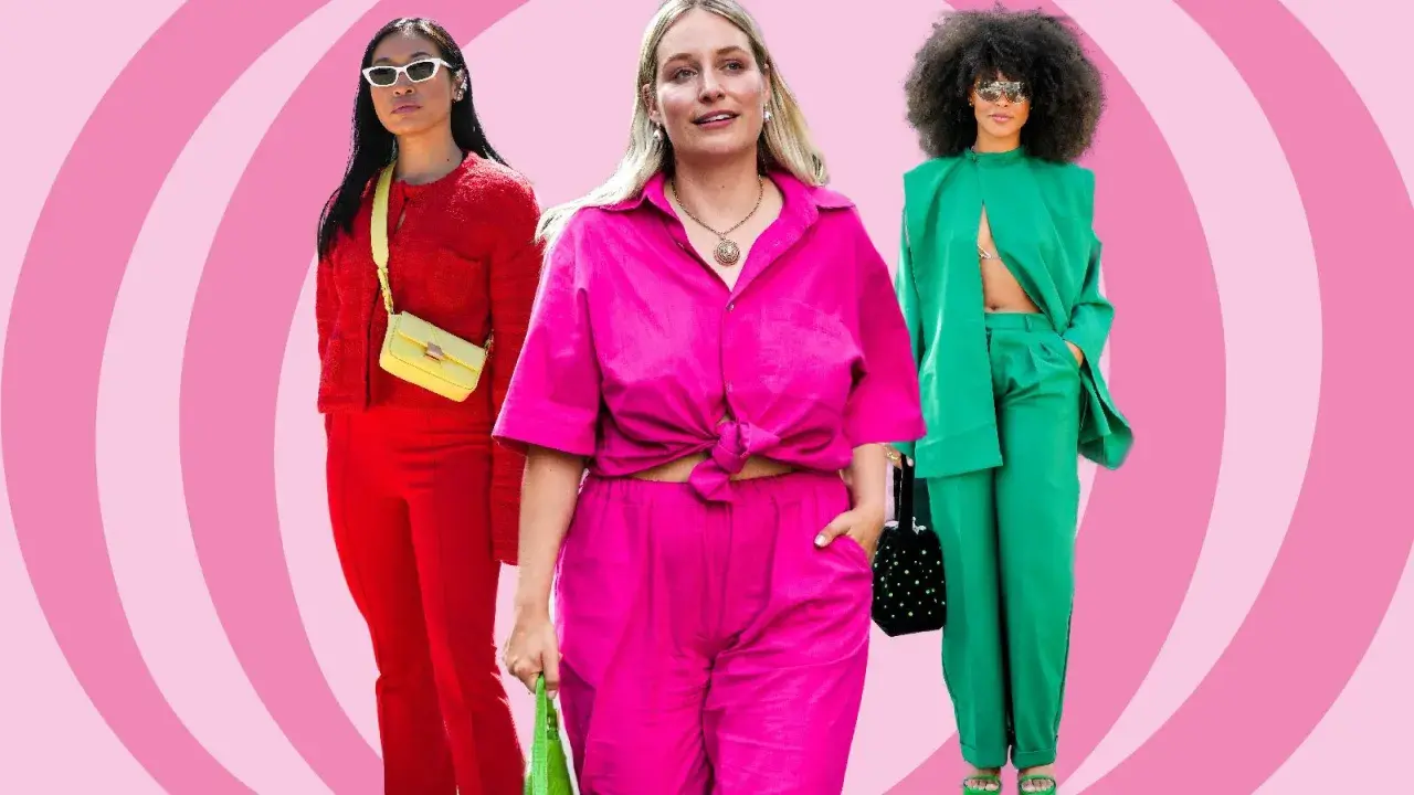Drei Frauen in auffälligen, monochromen Outfits: Rot, Pink und Grün. Sie präsentieren selbstbewusst ihre Looks.