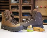 Braune Wanderschuhe, daneben ein Wachs und eine Bürste zur Pflege. So bleiben deine adidas Terrex Stiefel wie neu, auch nach der nächsten "Waschmaschine" aus Schlamm und Matsch.
