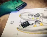 Ein Schuhdesigner skizziert einen Sneaker mit Schnürsystem. Ein grüner Schuhleisten liegt daneben.