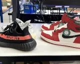 Zwei Paar Sneaker: ein schwarzer Yeezy Boost 350 mit rotem Streifen und ein weiß-roter Air Jordan 1. So erkennt man off white fake.