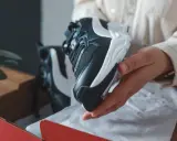 Schwarze und weiße Sneaker, die aus einer roten Box genommen werden. Sehen sie aus wie vapormax fake?