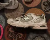 Ein schmutziger New Balance 530 Sneaker liegt auf einem gemusterten Teppich. Zeit, ihn zu waschen!