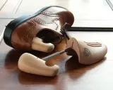 Holz-Schuhspanner für elegante Schuhe, die auch als Schuhspanner für Wanderschuhe dienen könnten, liegen neben einem braunen Lederschuh.
