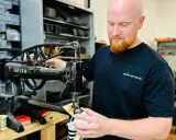Ein Schuster repariert Schuhe an einer alten Nähmaschine. Er ist ein Handwerker, der sich um das Schuhwerk kümmert.