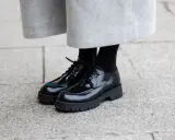 Schwarze Schnürschuhe mit dicker Sohle, ein moderner Schuh-Typ für Damen, kombiniert mit einem grauen Wollrock.