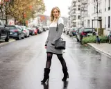 Stylische Frau im Strickkleid mit schwarzen Stiefeln und Tasche auf nasser Straße. Perfekte Antwort auf die Frage: welche schuhe zum strickkleid.