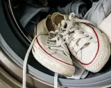 Weiße Superga Schuhe mit roten Streifen warten in der Waschmaschine auf ihren Waschgang.