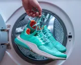 Skechers waschen wieviel Grad? Türkise Turnschuhe werden vor dem Waschen in der Waschmaschine gehalten.