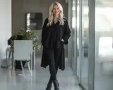 Eine Frau stylt eine schwarze Longbluse mit Leggings und Stiefeletten. Ein lässiger, aber schicker Look.