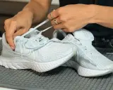 Hände binden hellblaue Nike Schuhe, bereit für die Waschmaschine.