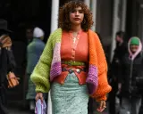 Bunte Strickjacke mit Ballonärmeln, die zeigt, wie man einen Cardigan kombinieren Damen kann. Dazu ein mintgrüner Rock und auffälliger Gürtel.