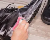 Schwarze Lederschuhe werden mit einem Schwamm und Seifenschaum gereinigt. Die Sohle und das Leder werden sorgfältig abgerieben, um sie wieder sauber zu machen.