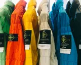 Bunte Stone Island Jacken mit dem ikonischen Patch. Ein Vergleich von Stone Island Patch original vs. fake ist hier gut erkennbar.
