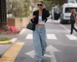 Frau in einem lässigen Baggy Jeans Outfit mit schwarzem Blazer und weißem Crop-Top, unterwegs in der Stadt.