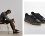Mann sitzt nachdenklich auf einem Stuhl, trägt schwarze Sneaker mit brauner Sohle. So sollten Schuhe sitzen: bequem und stilvoll.