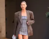 Frau in kariertem Blazer und gestreiftem Kleid. Der Blazer ist leicht zerknittert, als ob sie ihn gerade aus der Wäsche genommen hätte.