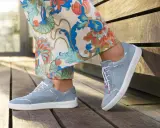 Blaue Wildlederschuhe mit weißer Sohle und dezenter Ziernaht am Schuh, kombiniert mit einer Hose mit floralem Muster.