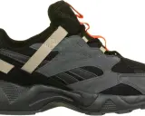 Reebok Aztrek 96: schwarzer Sneaker mit grauen Wildleder-Overlays, beige Akzenten und orangefarbenen Schlaufen.