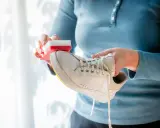 Person reinigt weiße Puma Schuhe mit einem Schwamm.