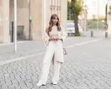 Eine Frau in einem cremefarbenen Outfit mit weiten Leinenhosen, das perfekt für den Sommer ist. So kann man Leinenhose kombinieren Damen!