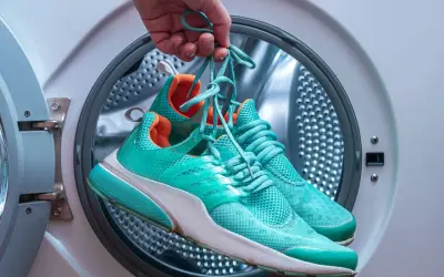 Skechers waschen wieviel Grad? Türkise Turnschuhe werden vor dem Waschen in der Waschmaschine gehalten.