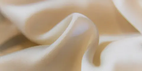 Sanfter Stoff in Beige, der sich sanft kräuselt. Ideal, um statische Aufladung zu verhindern und ein angenehmes Tragegefühl zu gewährleisten.