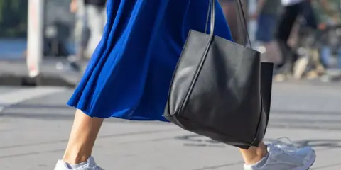 Ein blaues Kleid mit weißen Sneakern zum Kleid und einer schwarzen Tasche.