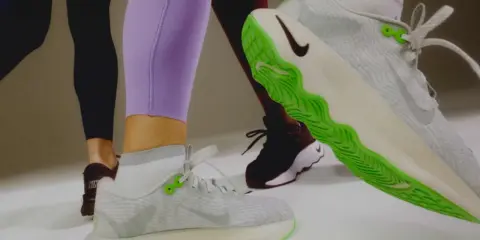 Sportliche Beine in Leggings und Sneakern. Ein Schuh mit leuchtend grüner Sohle zeigt, wie man Schuhe recyceln kann.