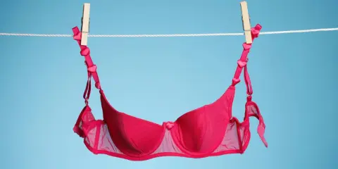 Ein roter BH mit Herzchen-Trägern trocknet an der Wäscheleine. Frisch gewaschen und bereit für den nächsten Einsatz.
