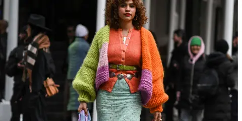 Bunte Strickjacke mit Ballonärmeln, die zeigt, wie man einen Cardigan kombinieren Damen kann. Dazu ein mintgrüner Rock und auffälliger Gürtel.
