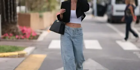 Frau in einem lässigen Baggy Jeans Outfit mit schwarzem Blazer und weißem Crop-Top, unterwegs in der Stadt.