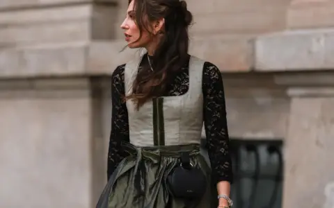 Eine Frau trägt eine graue Weste über einer schwarzen Spitzenbluse. So lässt sich die schwarze Bluse kombinieren für einen modernen Look.