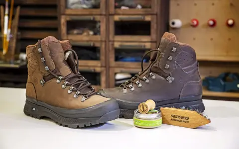 Braune Wanderschuhe, daneben ein Wachs und eine Bürste zur Pflege. So bleiben deine adidas Terrex Stiefel wie neu, auch nach der nächsten "Waschmaschine" aus Schlamm und Matsch.