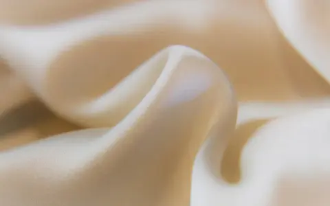 Sanfter Stoff in Beige, der sich sanft kräuselt. Ideal, um statische Aufladung zu verhindern und ein angenehmes Tragegefühl zu gewährleisten.