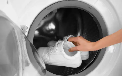 Weiße Sneaker werden in die Waschmaschine gelegt, um sie wieder sauber zu bekommen.