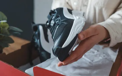 Schwarze und weiße Sneaker, die aus einer roten Box genommen werden. Sehen sie aus wie vapormax fake?