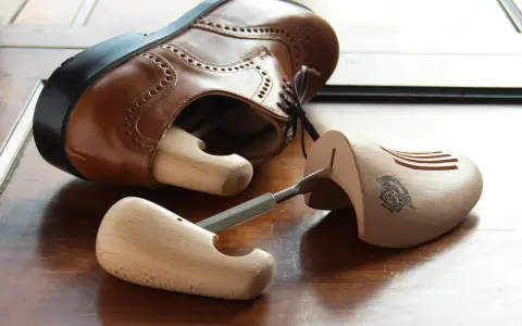 Holz-Schuhspanner für elegante Schuhe, die auch als Schuhspanner für Wanderschuhe dienen könnten, liegen neben einem braunen Lederschuh.