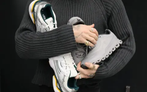 Person hält drei Paar Sneaker: weiße mit grünen Akzenten, graue und silberne. Ein Blick auf modernes shoe design.