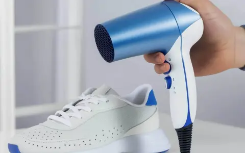 Ein weißer Sneaker mit blauen Akzenten, dessen **schuhe zu eng vorne** sind, wird mit einem blauen und weißen Föhn erwärmt.