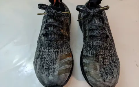 Zwei adidas bb3900 Laufschuhe mit grauem Camouflage-Muster und goldenen Streifen.