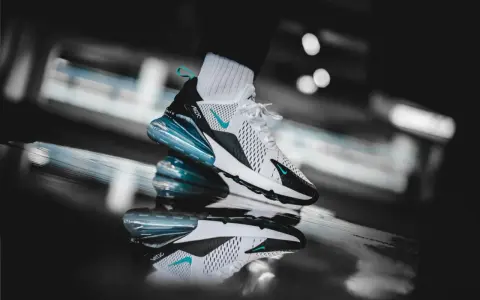 Ein stylischer Nike Air Max 270 in Weiß mit türkisen Akzenten, der auf einer spiegelnden Oberfläche steht. Ein zeitloser Klassiker unter den Nike Air Max alte Modelle.