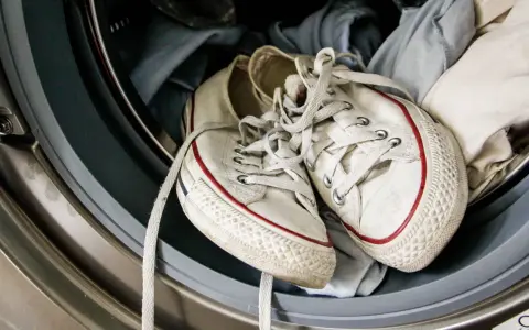 Weiße Superga Schuhe mit roten Streifen warten in der Waschmaschine auf ihren Waschgang.